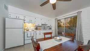 A compact kitchen with white cabinets, a wooden dining table, and a ceiling fan. - Cozy / Spotless / Central / Remodeled / 2 BR 1 BA (Tucson)