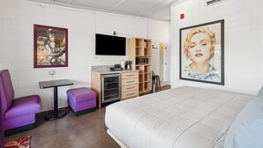 Una habitación de hotel moderna con cama, escritorio, silla y televisor.