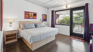A bedroom with a bed, nightstand, and wall art.