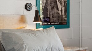 A bedroom with a bed, a wall-mounted lamp, and a framed poster on the wall. - Boutique Vera Hotel Room 403: King Room in the Heart of Folly Beach (Folly Beach)