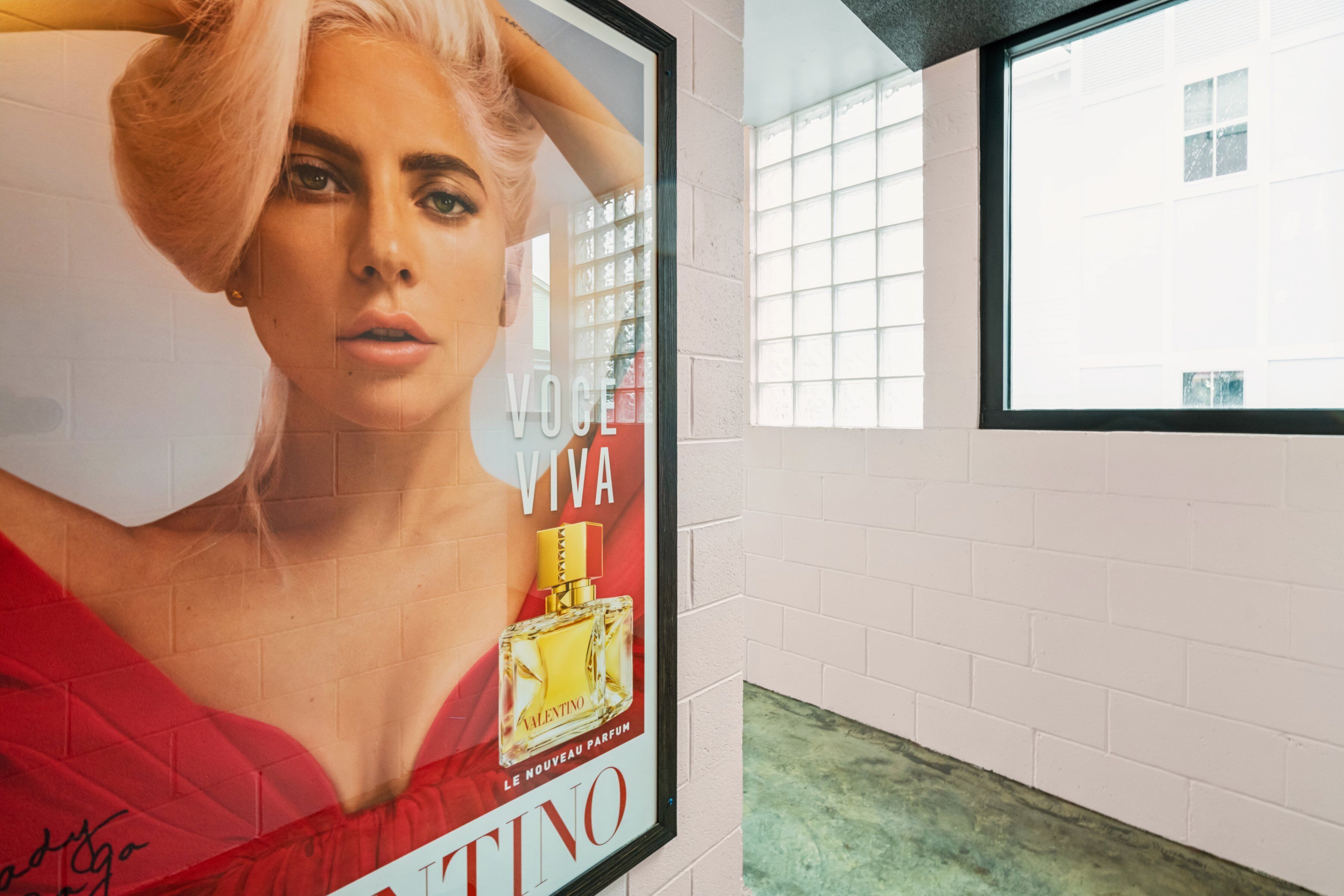 A framed advertisement for a perfume on a wall.