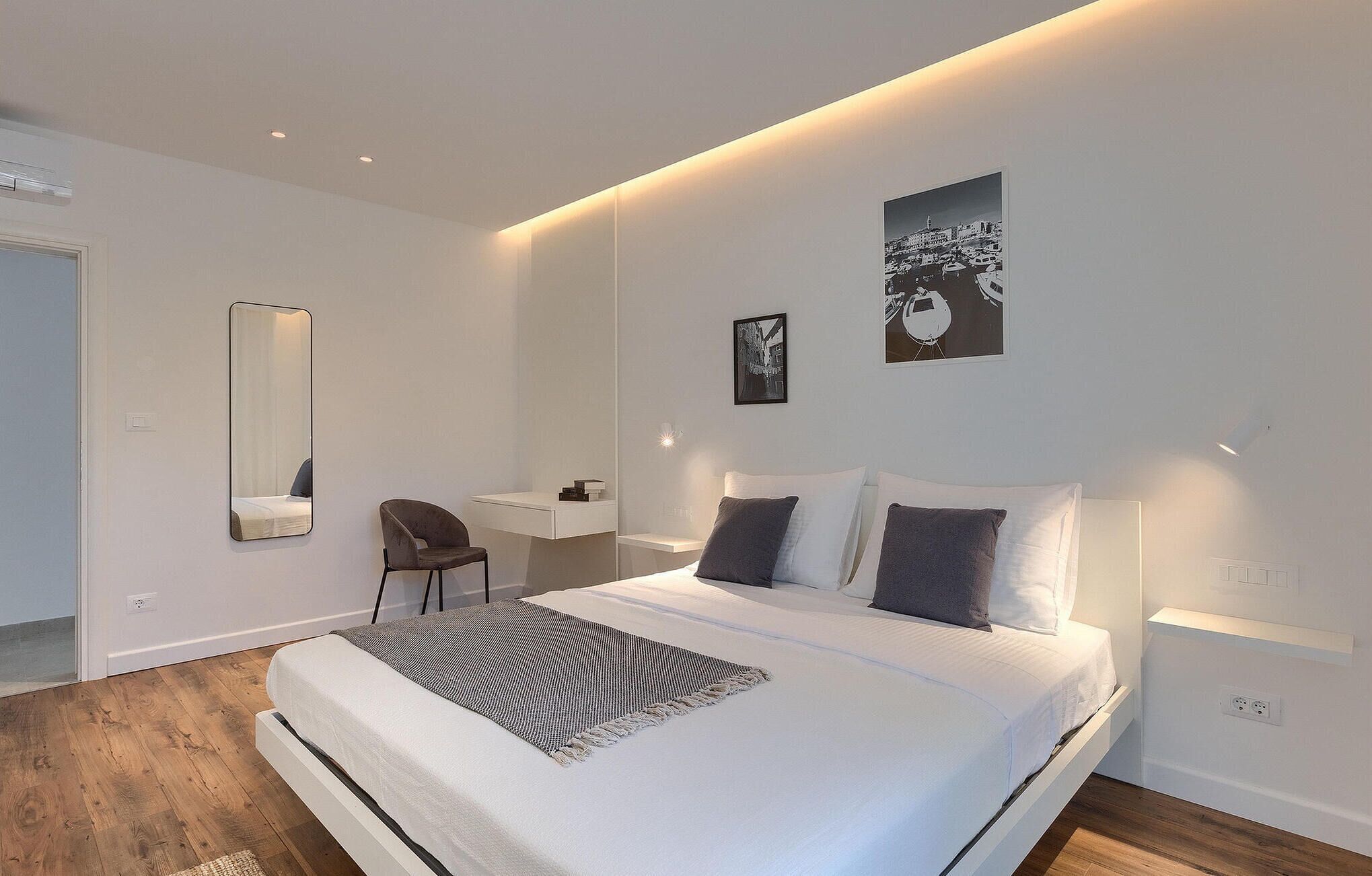 Ein modernes Schlafzimmer mit einem großen Bett, einem Nachttisch, einem Sessel und zwei an der Wand befestigten Kunstwerken.