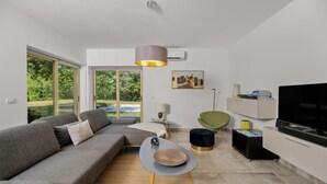 A modern living room with a grey sofa, a unique table, a TV, and a painting on the wall. - Stunning home in Labin - Rabac (Labin - Rabac)