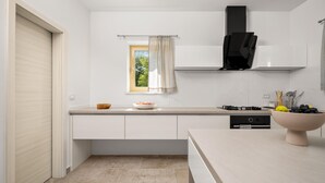 A modern kitchen with white cabinetry, a window with a view, a built-in oven, and a sink. - Stunning home in Labin - Rabac (Labin - Rabac)