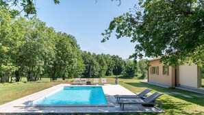 A rectangular swimming pool with lounge chairs and a small table, surrounded by a grassy lawn and trees. - Stunning home in Labin - Rabac (Labin - Rabac)