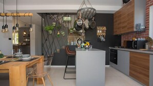 Une cuisine moderne dotée d’un îlot central, de casseroles suspendues et de divers ustensiles accrochés au mur.