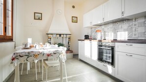A kitchen with white cabinets, a tiled backsplash, and a stove. There is a dining table with chairs and a small plant. - Stunning home in Ponte Buggianese (Ponte Buggianese)