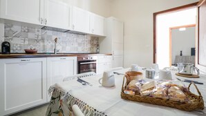 A kitchen with white cabinets, a tiled backsplash, a coffee maker, and a table set with bread and cups. - Stunning home in Ponte Buggianese (Ponte Buggianese)