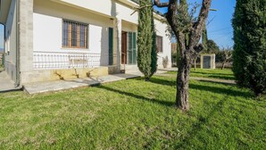 A white building with a stone base, a small porch, and a grassy lawn with a tree. - Stunning home in Ponte Buggianese (Ponte Buggianese)