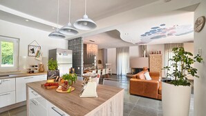 Une cuisine moderne avec un îlot central en bois, des armoires blanches et des luminaires suspendus.