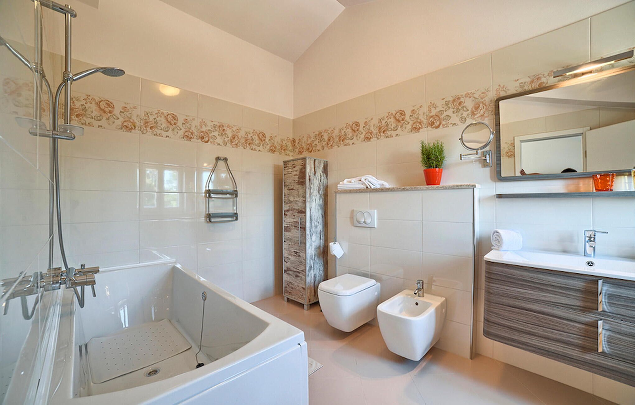 A modern bathroom with a bathtub, a bidet, a toilet, and a vanity with a mirror.