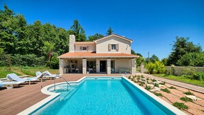Une maison à deux étages avec une piscine, un patio couvert et un jardin.