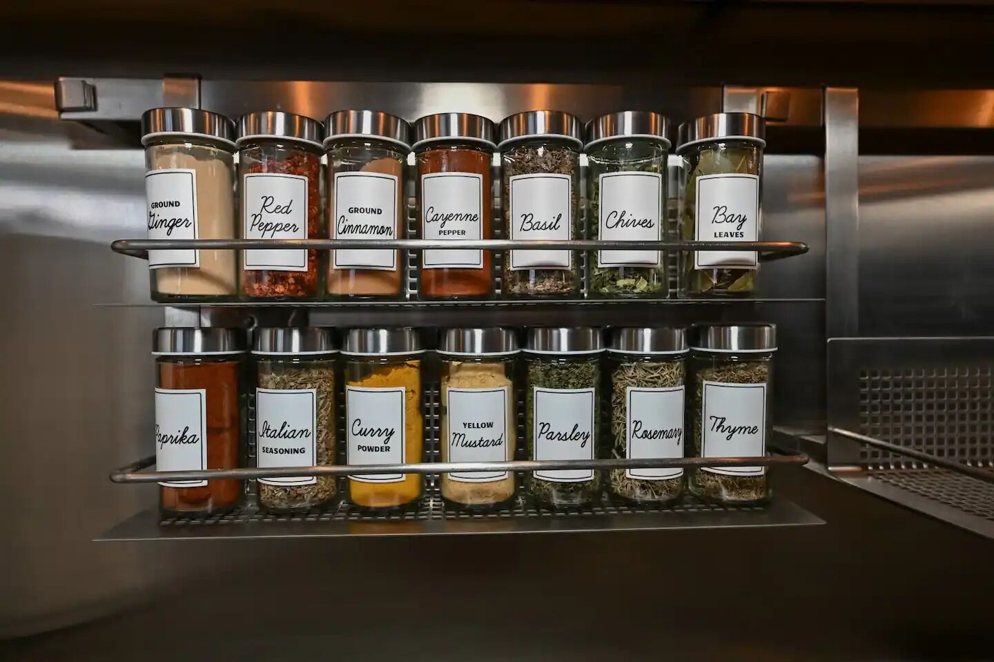 A spice rack with labeled containers of various spices and seasonings.
