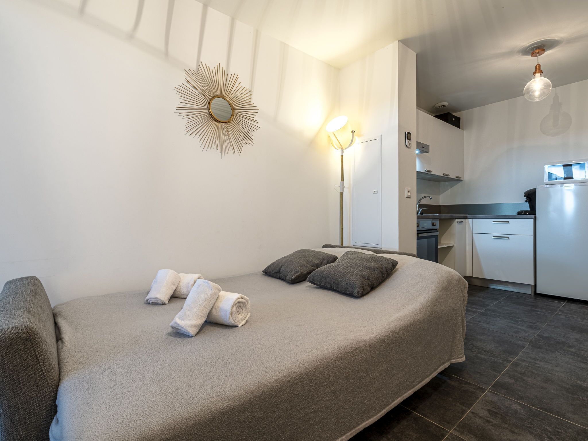 Ein modernes Schlafzimmer mit Schlafsofa, einem Dekomirror und einer Nachttischlampe.