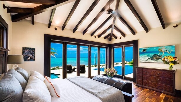 Un dormitorio con una cama grande, un aparador y vista al océano.