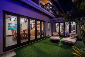 A modern house with a dining area, kitchen, and living room with a green artificial lawn.