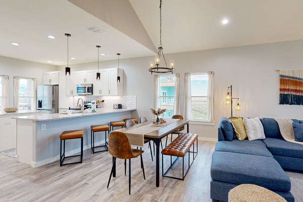 A modern kitchen with white cabinets, a central island, and pendant lighting. - Shared Pool, Shared Hot Tub, Pet Friendly (Port Aransas)