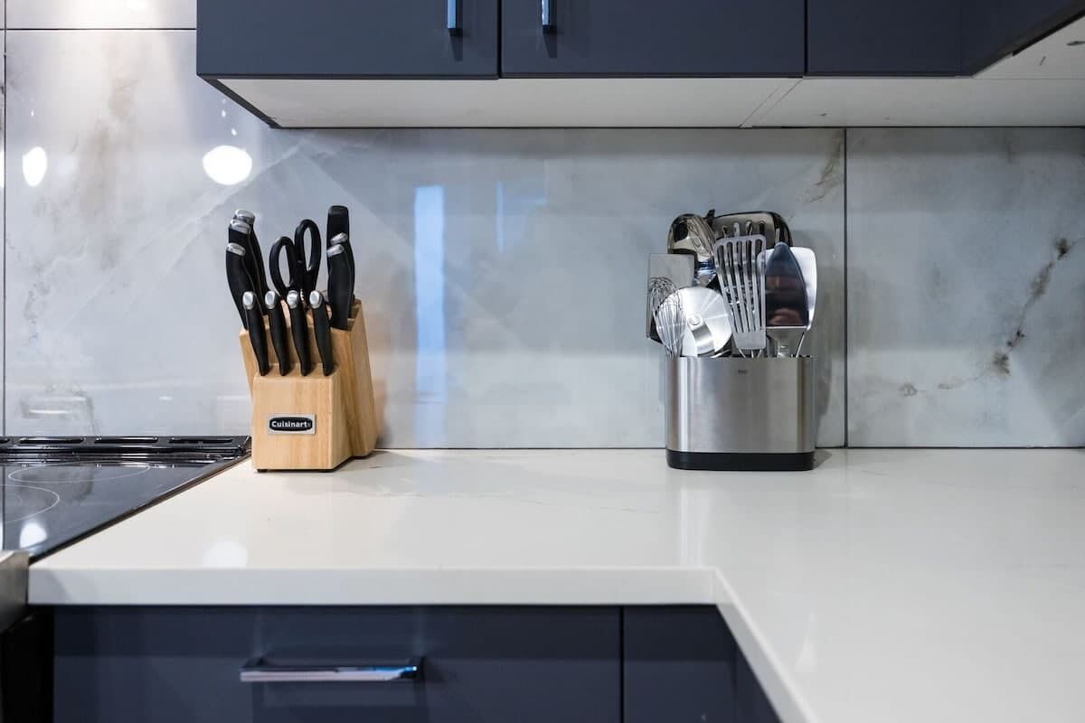 A kitchen with a white countertop, a knife block, and a utensil holder.