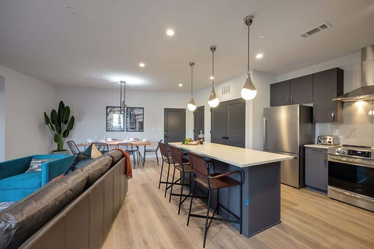 A modern kitchen with a central island, bar stools, and stainless steel appliances.