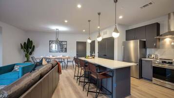 A modern kitchen with a central island, bar stools, and stainless steel appliances.