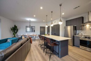 Una cocina moderna con una isla central, taburetes de bar y electrodomésticos de acero inoxidable.