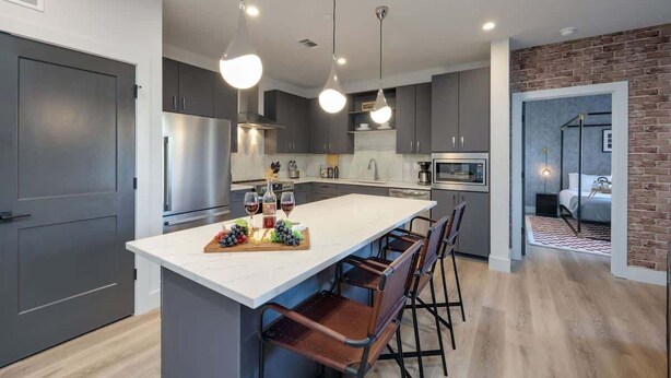 A modern kitchen with a central island, bar stools, and pendant lighting.
