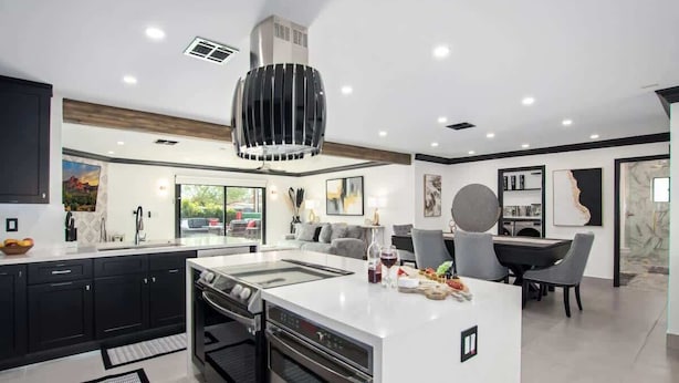 A modern kitchen with a central island, built-in ovens, and a large pendant light.