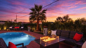 A pool area with a fire feature, outdoor seating, and a palm tree.