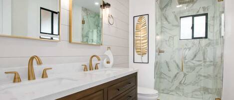 A modern bathroom with a dual sink vanity, a large mirror, and a glass shower enclosure.