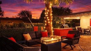 An outdoor seating area with a fire feature, a bar, and a palm tree.
