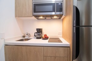 Una cocina moderna con electrodomésticos de acero inoxidable, armarios de madera y encimera blanca.