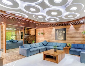 A modern living room with a sectional sofa, a coffee table, and a wooden ceiling with circular patterns.