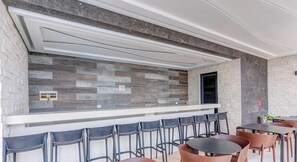 A bar area with a stone wall backdrop, seating arrangement, and a no-smoking sign. - Oceanview Infinity Pool, Steps to 5th Ave & Beach (Playa del Carmen)