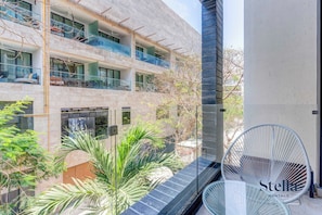 A modern building with balconies, a glass door, and a chair. - Oceanview Infinity Pool, Steps to 5th Ave & Beach (Playa del Carmen)