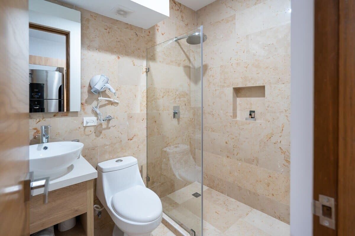 A modern bathroom with a glass-enclosed shower, a white toilet, and a sink.