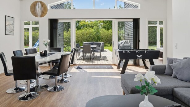 Een ruime woonruimte met een eettafel, stoelen, een bank en een barbecue.