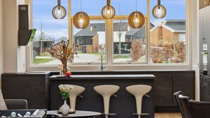 Een moderne keuken met een groot raam, hanglampen en een bar voorzien van krukjes.