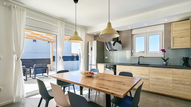 Une cuisine moderne avec une table et des chaises en bois, un four encastré et une fenêtre offrant une belle vue.