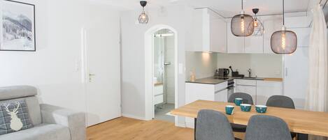 Een moderne keuken met een houten tafel en stoelen, een grijze bank en een lijst met een foto aan de muur.