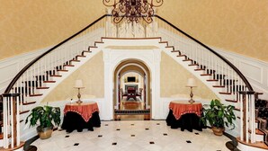 Eine prächtige Treppe mit einer Chandelier, die zu einem Essbereich mit Kamin führt.