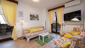 Een woonkamer met een bank, een salontafel, een televisie en een radiator.