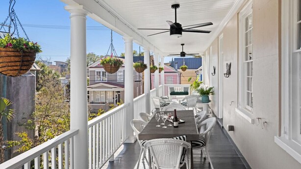 A covered porch with white wicker furniture, hanging flower baskets, and a ceiling fan. - 6C at Saint Philip Square, One Block to King, Classic Charleston Comfort (Charleston)