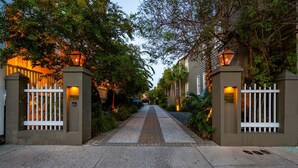 A gated entrance with a pathway leading to a building, surrounded by greenery and illuminated by wall-mounted lights. - 6A at Saint Philip Square, One Block to King, Classic Charleston Comfort (Charleston)