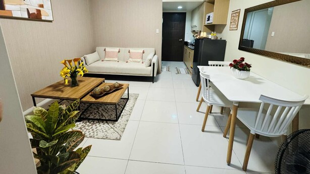 A compact living space with a sofa, dining table, chairs, a small kitchen area, and a refrigerator. - Brenthill Condominium (Baguio)