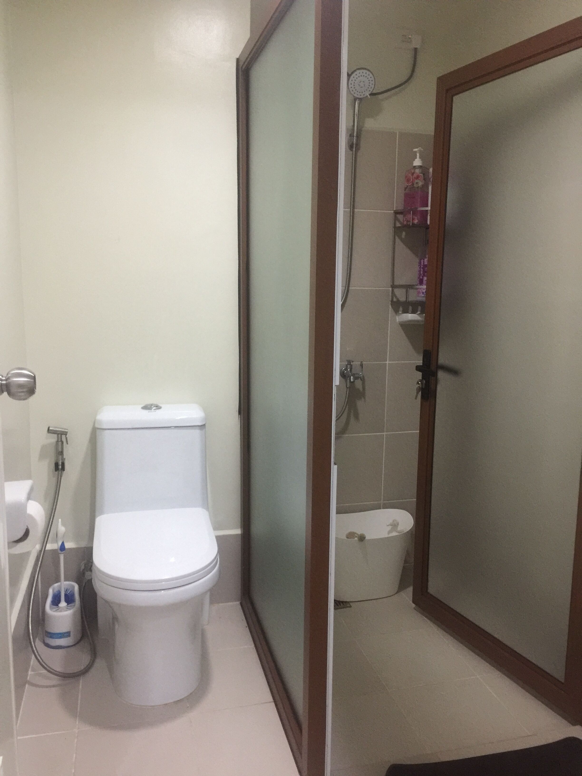 Un baño con inodoro, ducha y puerta de vidrio.