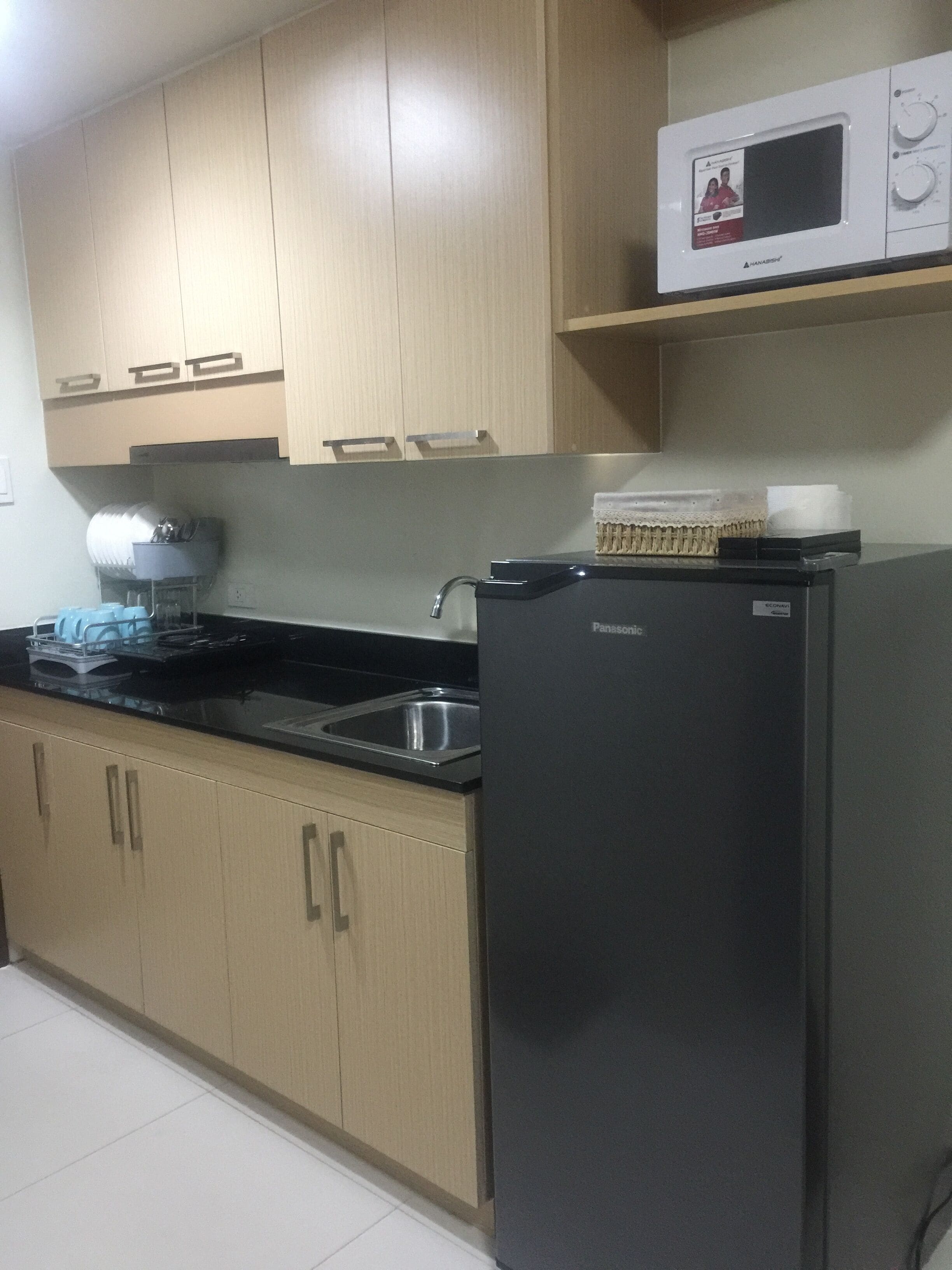 A kitchen with wooden cabinets, a black refrigerator, a microwave, and a sink.