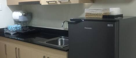 A kitchen with wooden cabinets, a black refrigerator, a microwave, and a sink.