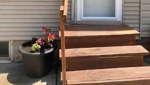 A house with a front door, a mailbox, and a wooden staircase leading to the door.