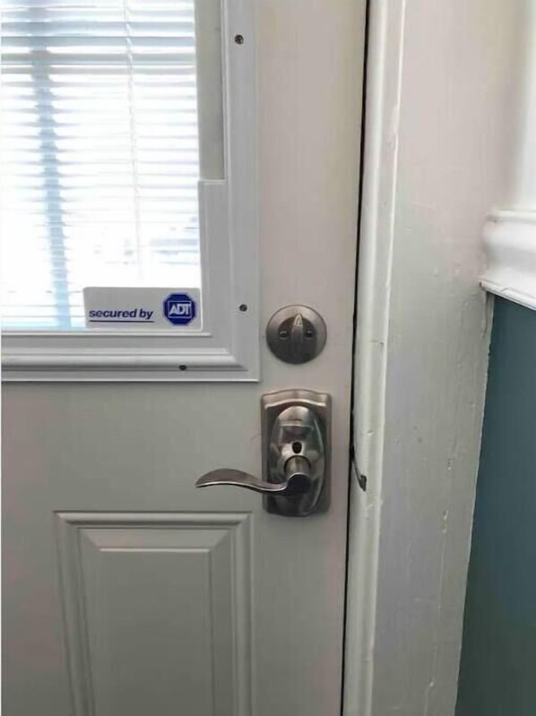 Una puerta blanca con un picaporte plateado y un ventanal encima.