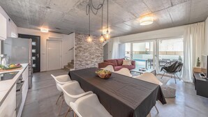 Una cocina moderna con horno integrado y comedor con mesa oscura y sillas blancas.